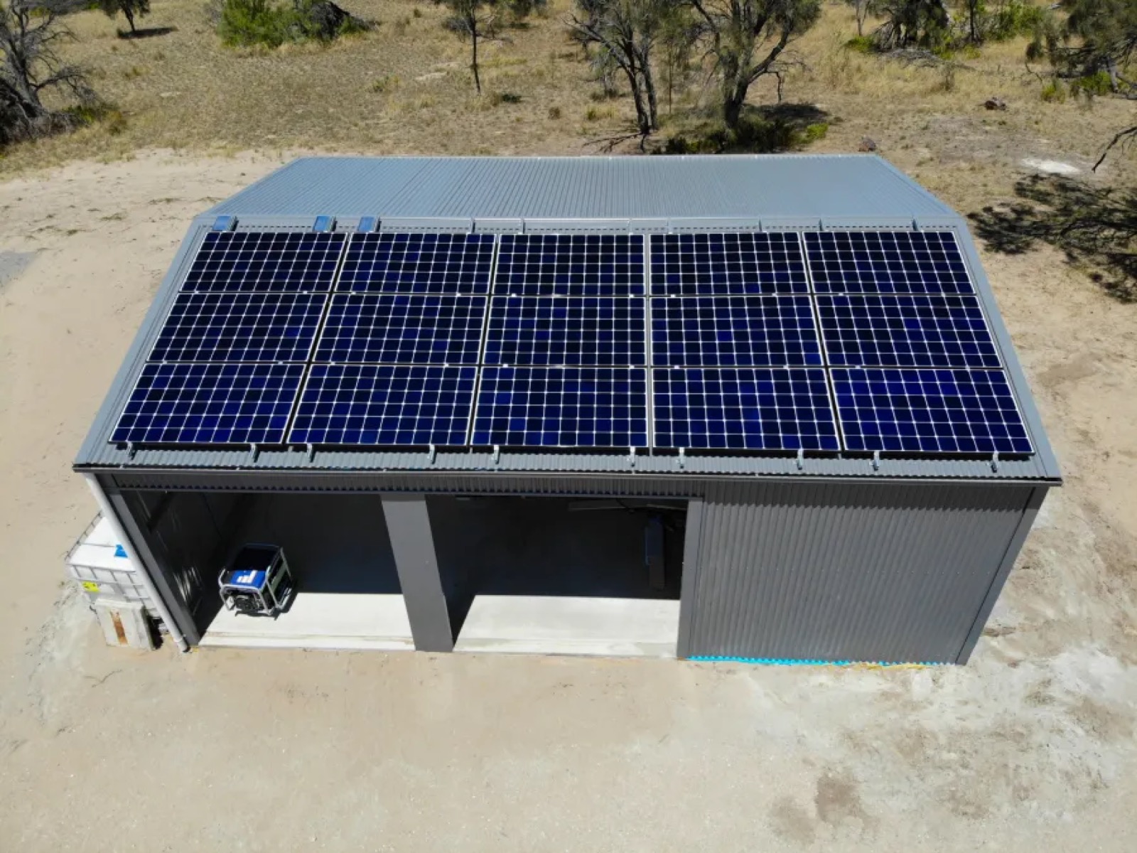 Aerial view of full solar array covering a tin shed roof on a remote property